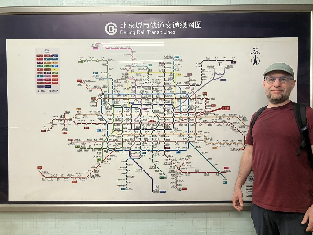 Author stands next to extensive metro map of Beijing Rail Transit Lines