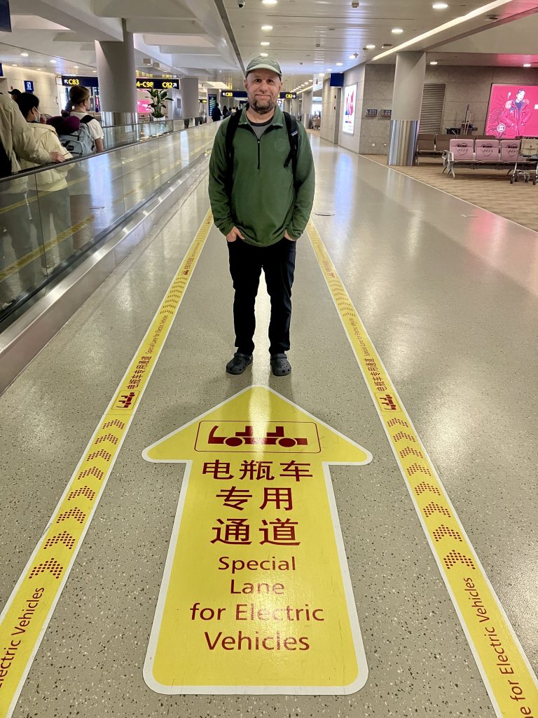 Author at airport, standing in middle of "Special Lane for Electric Vehicles"