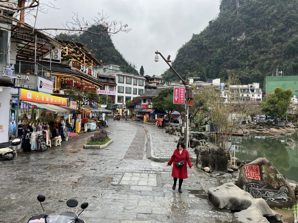 Daytime view of cobblestone street with person walking on the side, and moped in foreground