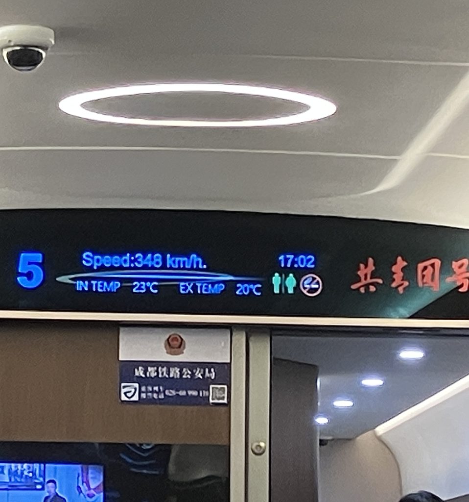 Monitor inside train displaying: Speed: 348 km/h.