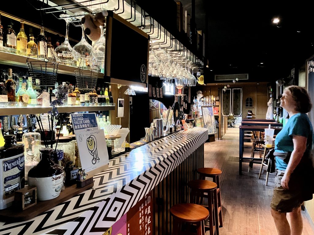 Woman standing in front of extravagent bar inside a repurposed railroad car.

