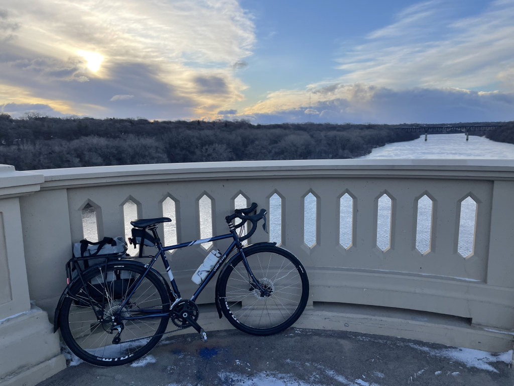 A bike rests on a rounded bridge overlooking the Mississippi River.