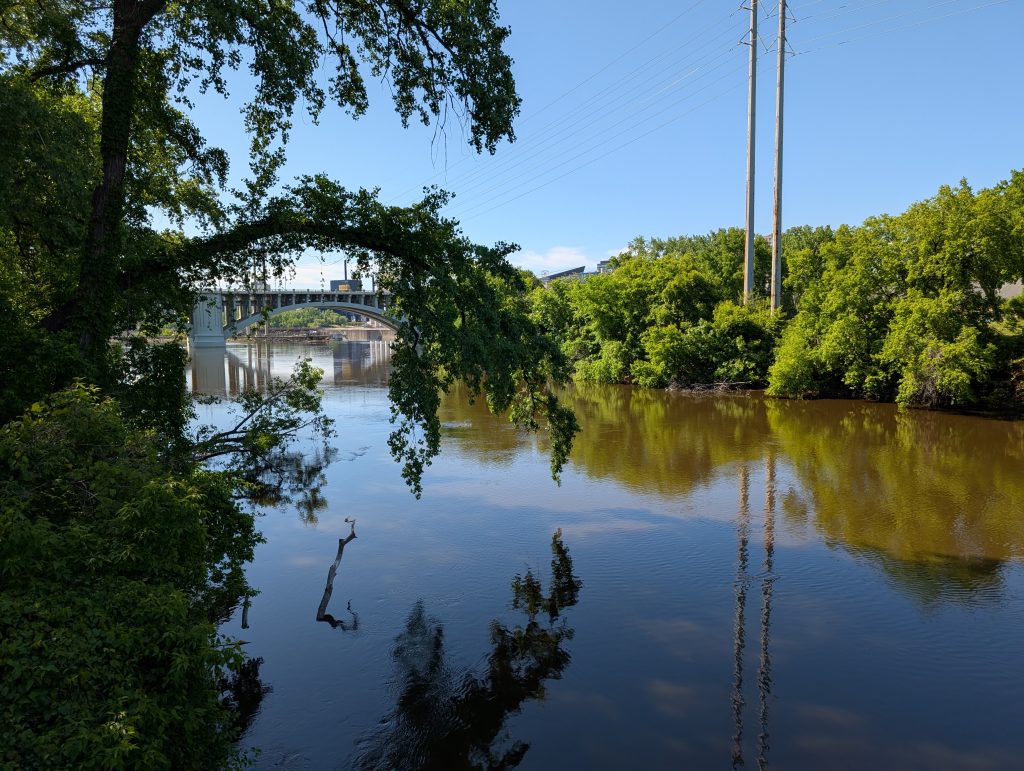 Tranquil river channel with arched bridge in background