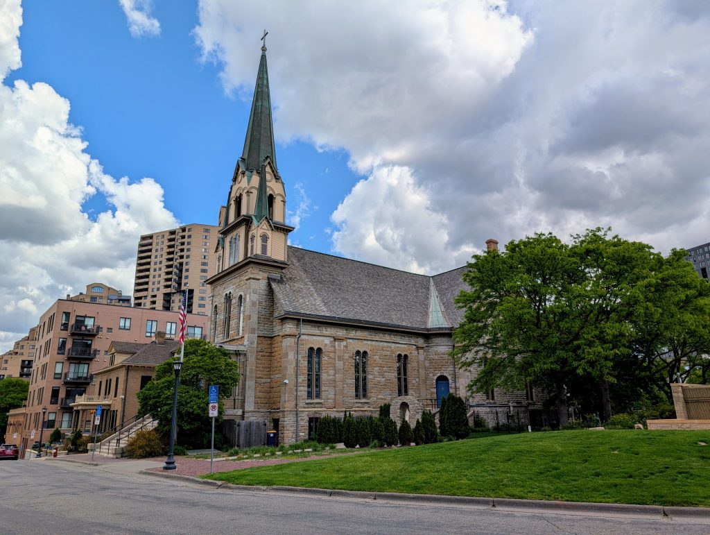 Stone church with bell tower on the front flanked by two smaller steeples.