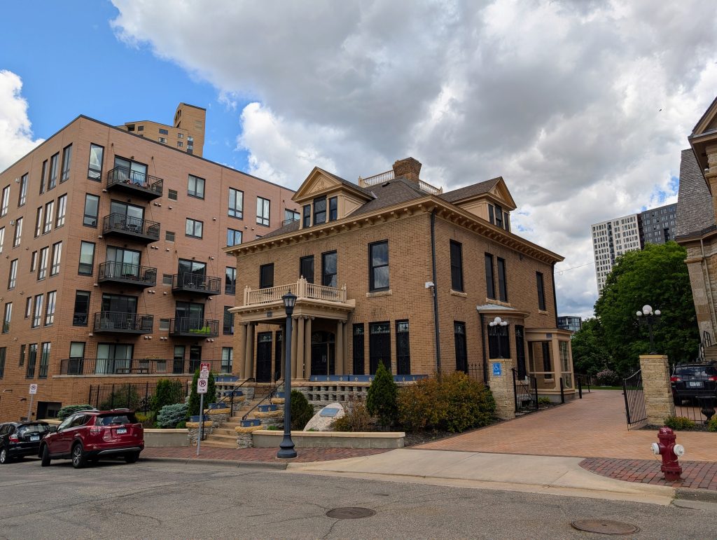 Two story brick-faced four-square house with dormers.