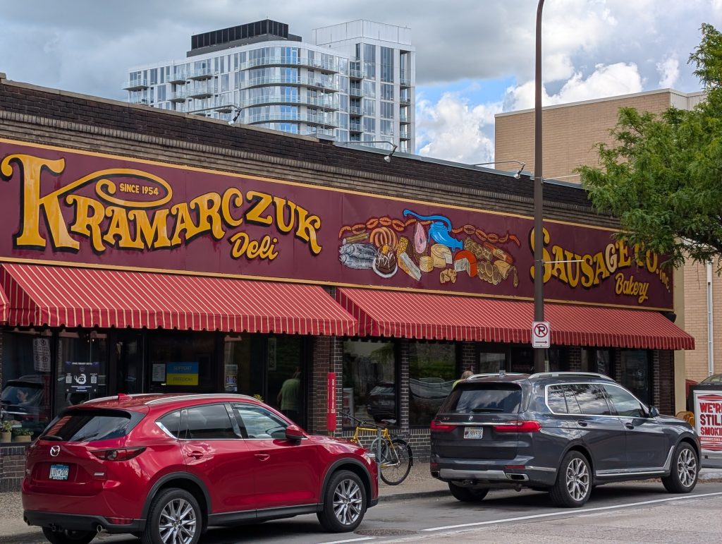 Retail facade with awnings and signage for Kramarczuk Deli, Sausage Co., and Bakery since 1954.