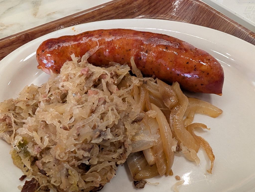 White plate with Ukrainian sausage with sauerkraut and onions.