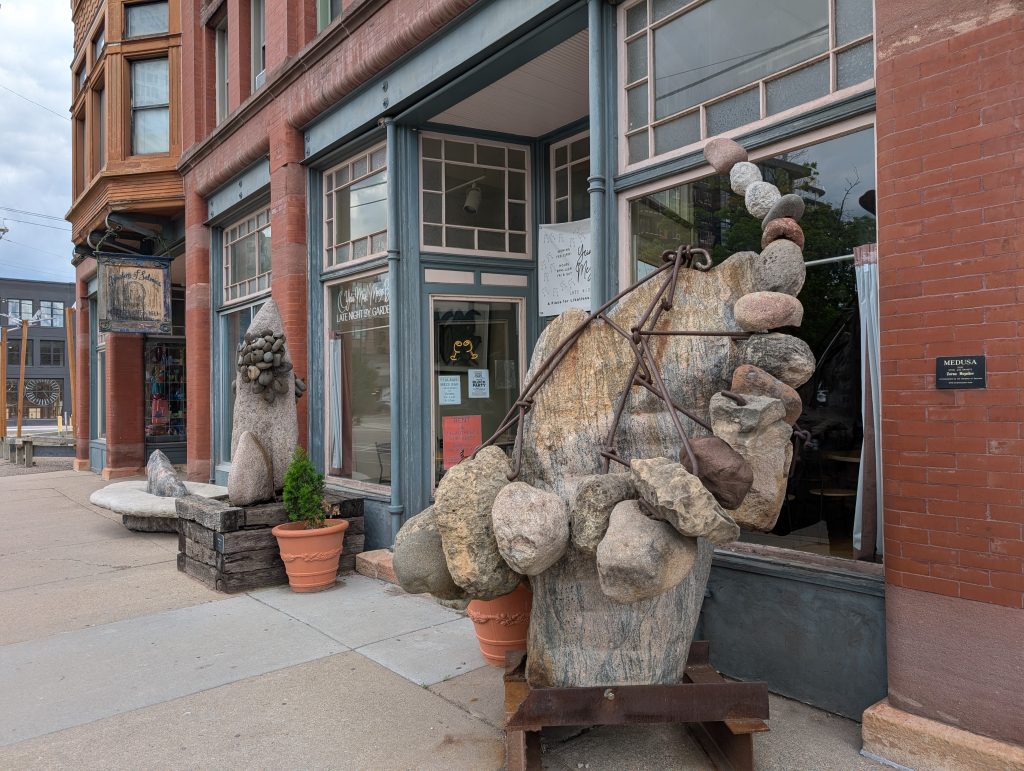 Steel and granite sculpture in front of building.