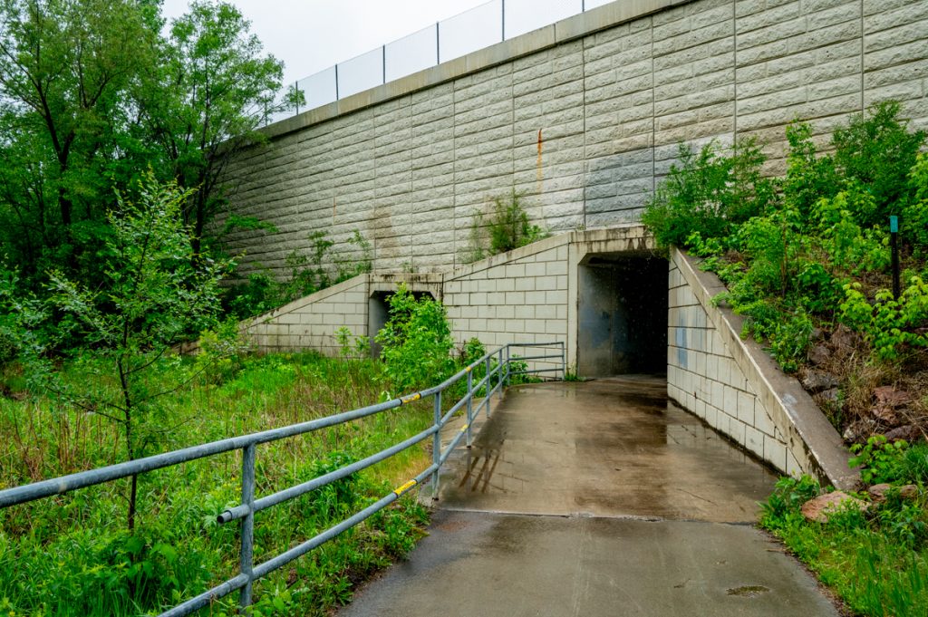 An opening to an underpass with greenery surrounding a paved trail on the Jonathan Trails 