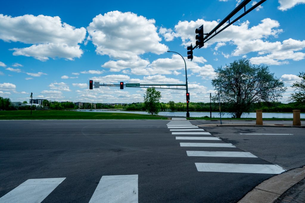 A crosswalk and cloudy blue skies leading to a park at SouthWest Station