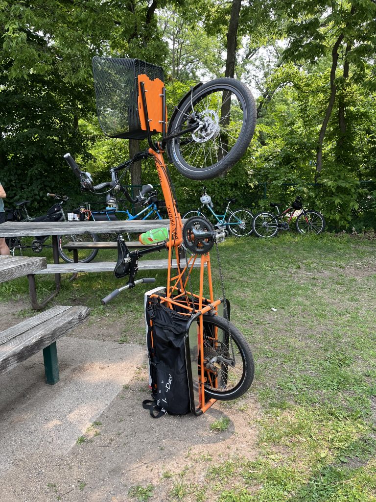 An orange cargo bike stands on end for easy vertical storage.