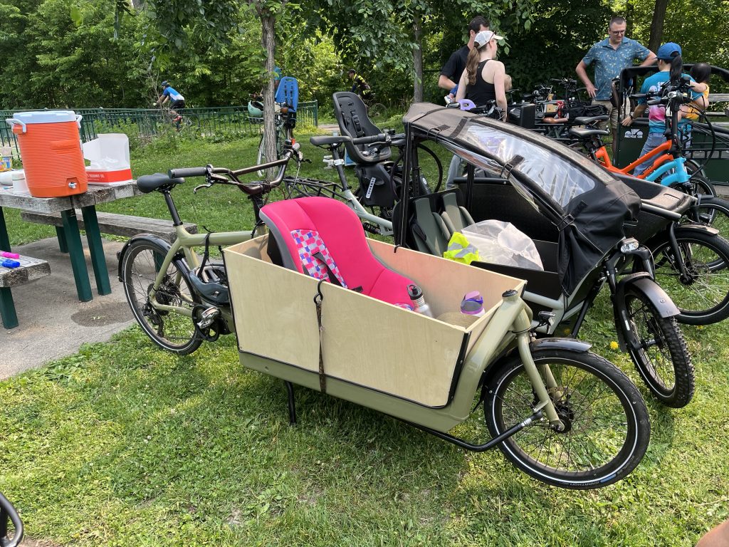 A cargo bike with a protected seat and bucket for a child to ride in.