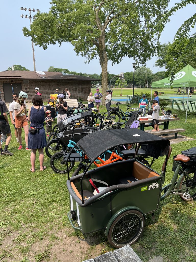 With cargo bikes in the foreground, adults and children look over the many bikes on display.