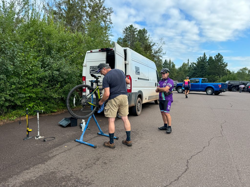 Two people checking over a bike in the parking lot. 
