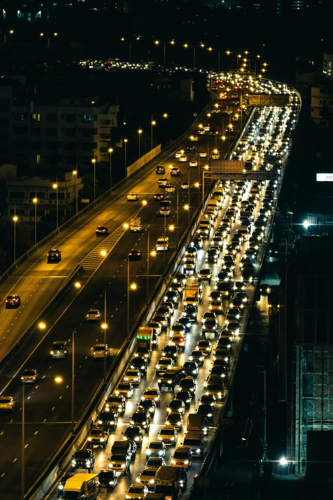 An overview of nighttime urban traffic, with four lanes bumper to bumper.
