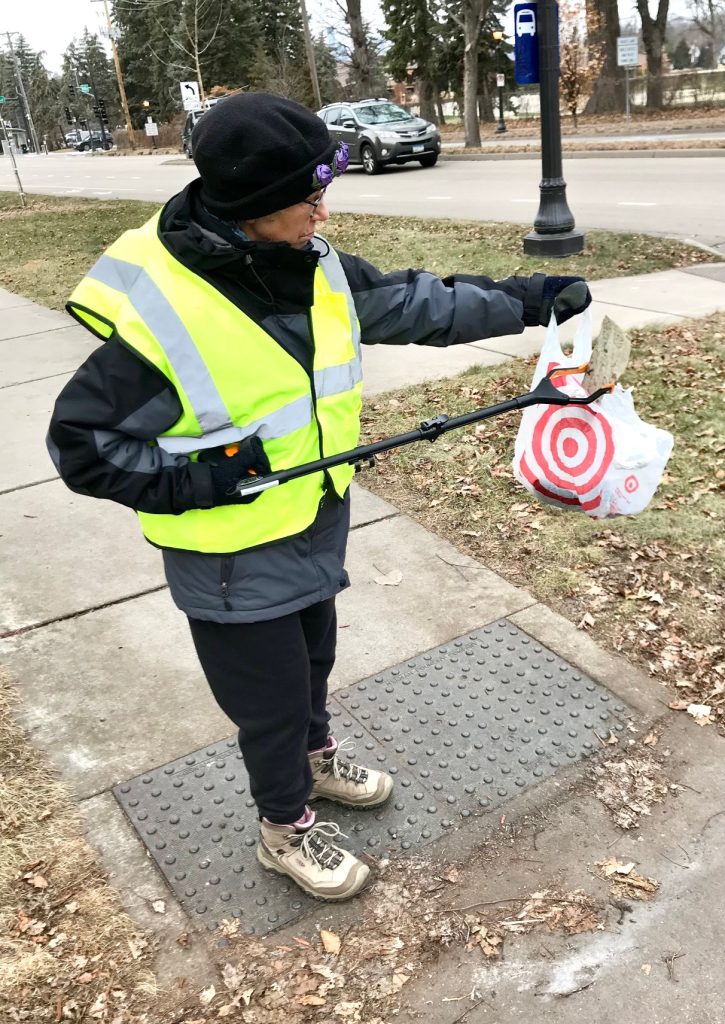 Person in a reflective vest putting litter in a bag