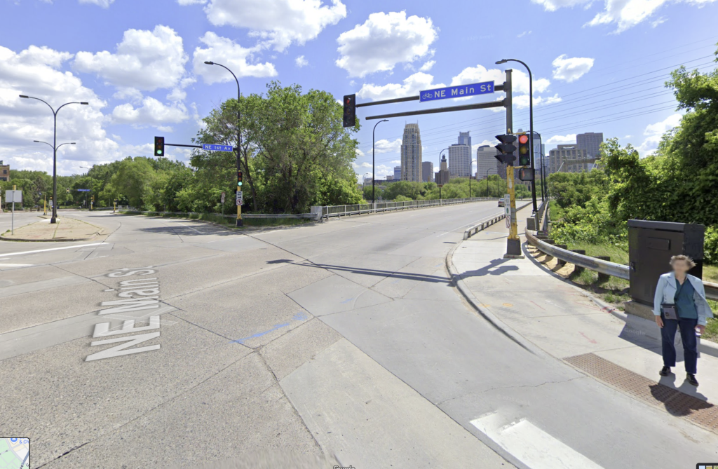 A look at a traffic intersection with city buildings and trees in the background.