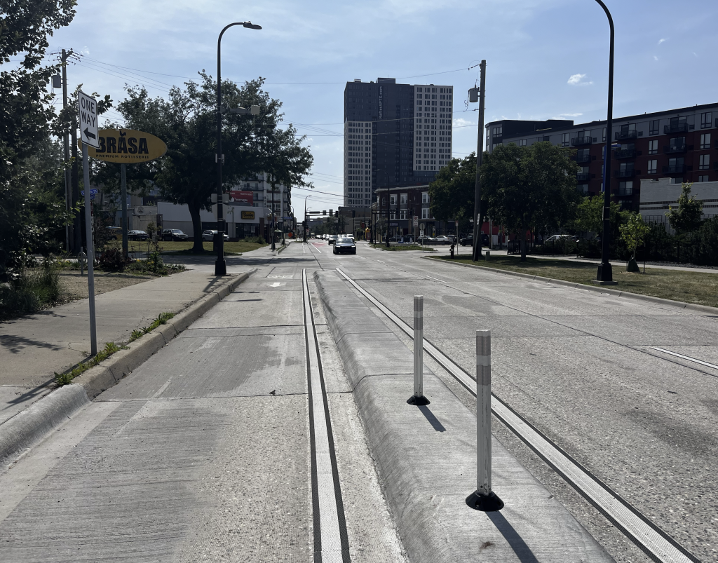 Street view with a separated bike lake with a raised divider between the bike lane and car lanes. 