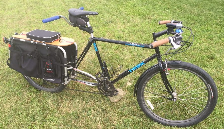 A black cargo like with beige handlebars and blue lettering. A large cargo pack wraps around the rear wheel. 