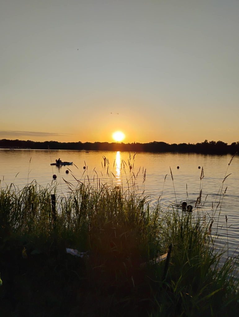 Sunset over Lake Nokomis, a few riders brought swim suits and cooled off in the waters. A canoe can be seen in the middle distance