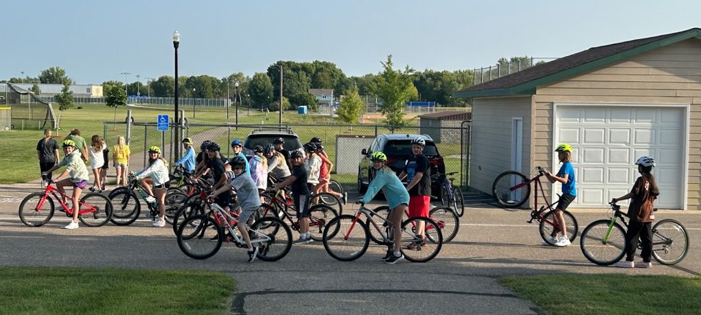 More than a dozen students line up in a school parking lot with their bikes in Hutchinson, Minnesota, as they prepare for a group ride.