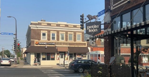 The intersection of Nicollet Ave and 38th Street in Kingfield showing cars and pedestrians. A sign reads "Petite Leon" with a lion on it. A second store has a sign saying "boost mobile"