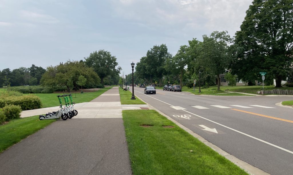 Looking south on the off-street trail along Cleveland Avenue in St. Paul. Four e-scooters sit on the edge of the trail.
