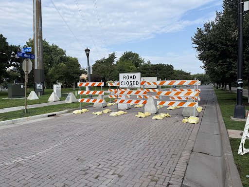 Temporary barriers, concrete bollards and a "Road Closed" sign block vehicular access to Main Street.