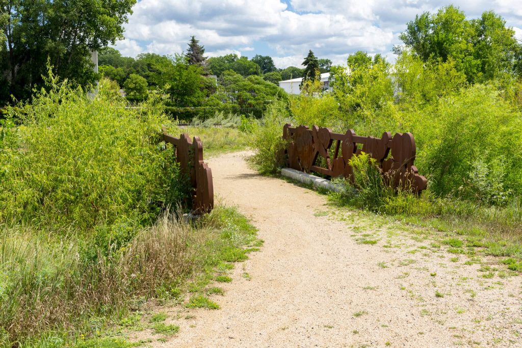 A gravel path crosses a bridge and through the nature sanctuary.