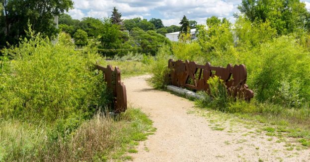 A gravel path crosses a bridge and through the nature sanctuary.