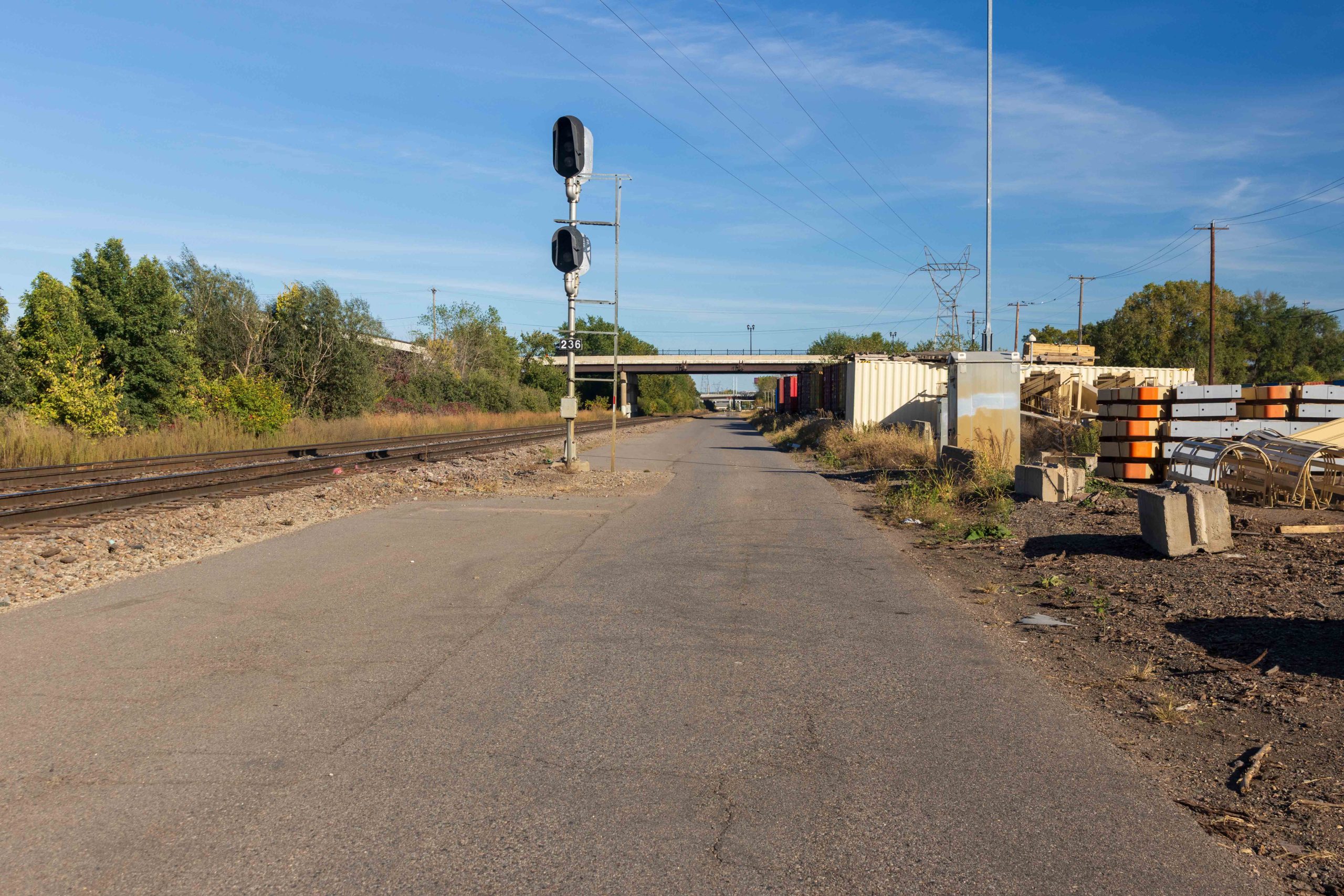 A railroad signal and a bridge over the paved railroad roadway.
