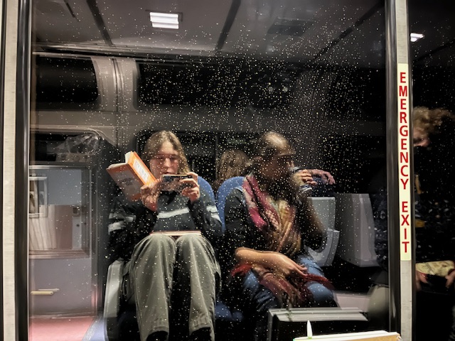 People in train seats on the other side of glass