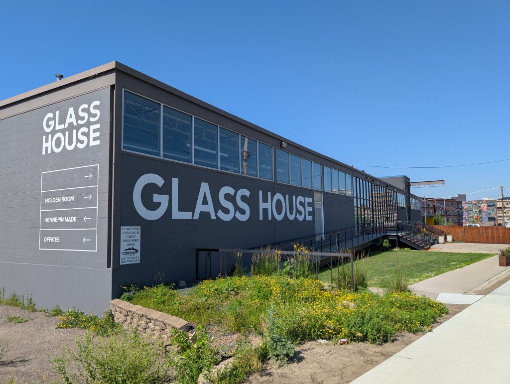 Grey cement-block building with bold white "GLASS HOUSE"