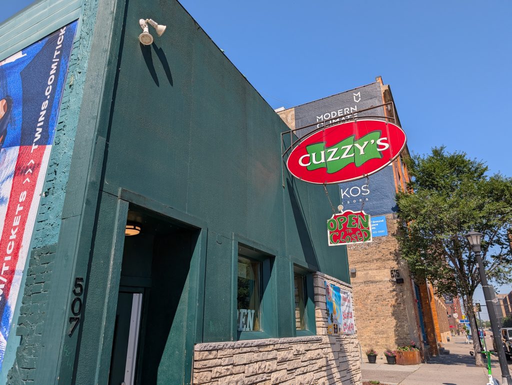 Small green building with bold red, white, and green signage for Cuzzy's