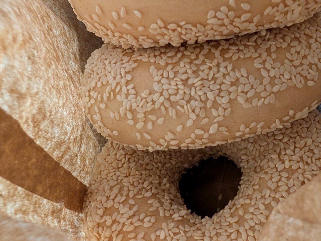 Three sesame bagels in a paper bag