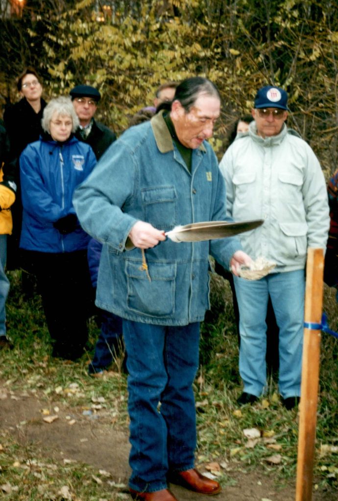 A Native American spiritual leader holding an object and blessing the site.