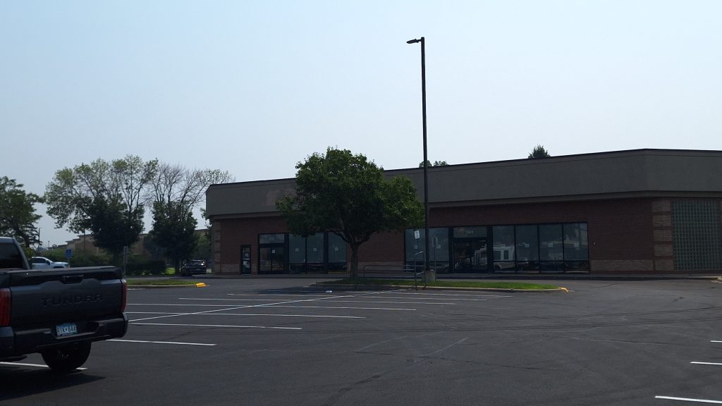 An empty strip mall displays the remnants of a removed Petco sign.