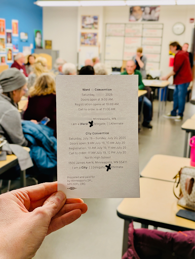 A card indicating ward and city convention delegate status held in front of people in a classroom