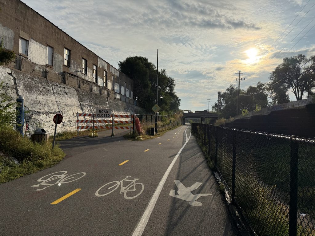 Looking east on the Midtown Greenway showing the Nicollet Ave bridge in the distance, and a road closed sign blocking access the the ramp from the greenway to Nicollet Ave.