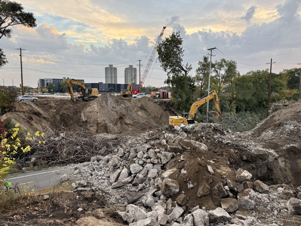 A pile of twisted rebar and some streetcar rail sits next to an even larger pile of concrete and dirt where the Nicollet Ave bridge once stood.