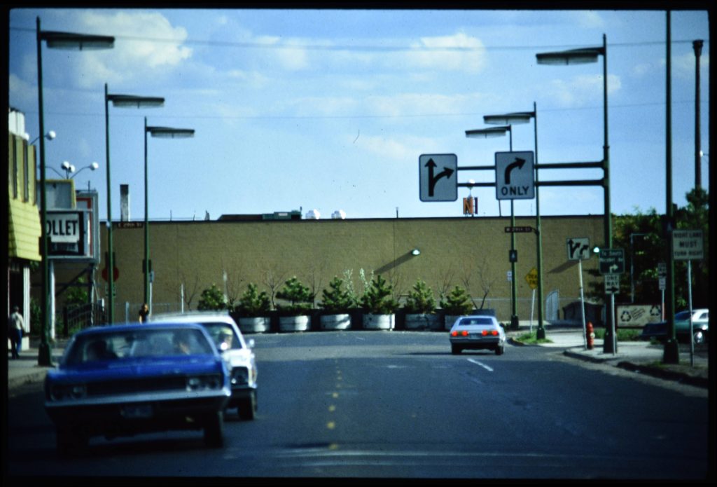 Looking south on Nicollet Ave from 28th St showing the back of the Kmart store, and planters at the edge of the bridge over the 29th St railroad tracks.