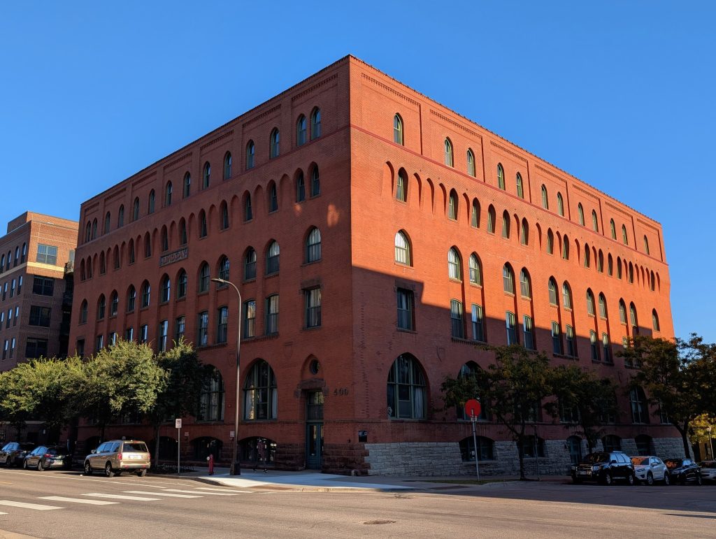 red brick building with gothic arches, top of right side in sun, rest in shadow