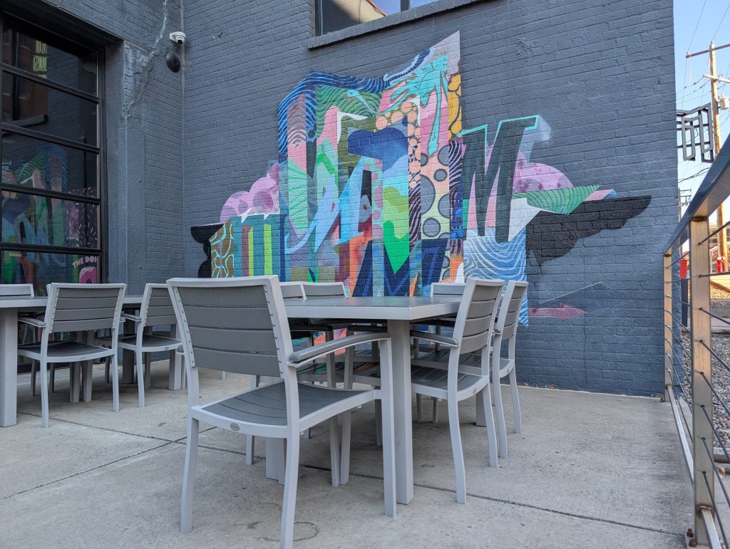 patio with tables, chairs, and a mural