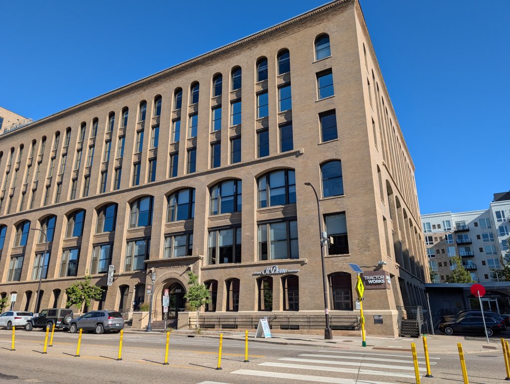 six-story large corner building in cream-colored brick with arched entryway