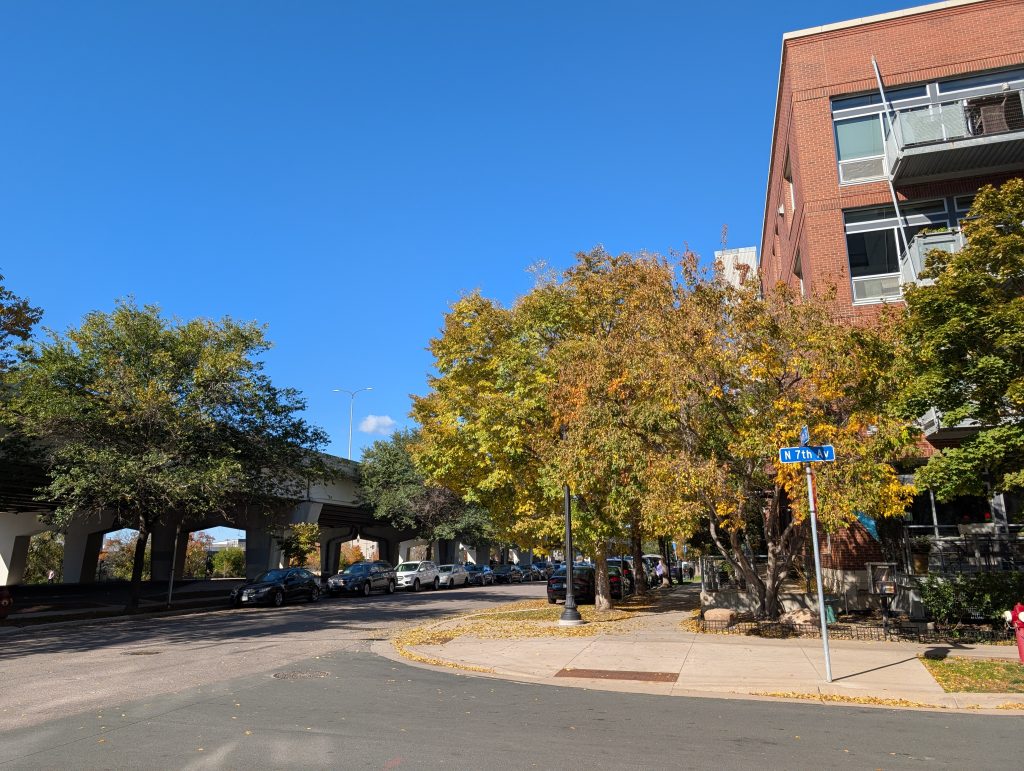 tree-lined street corner with viaduct in background