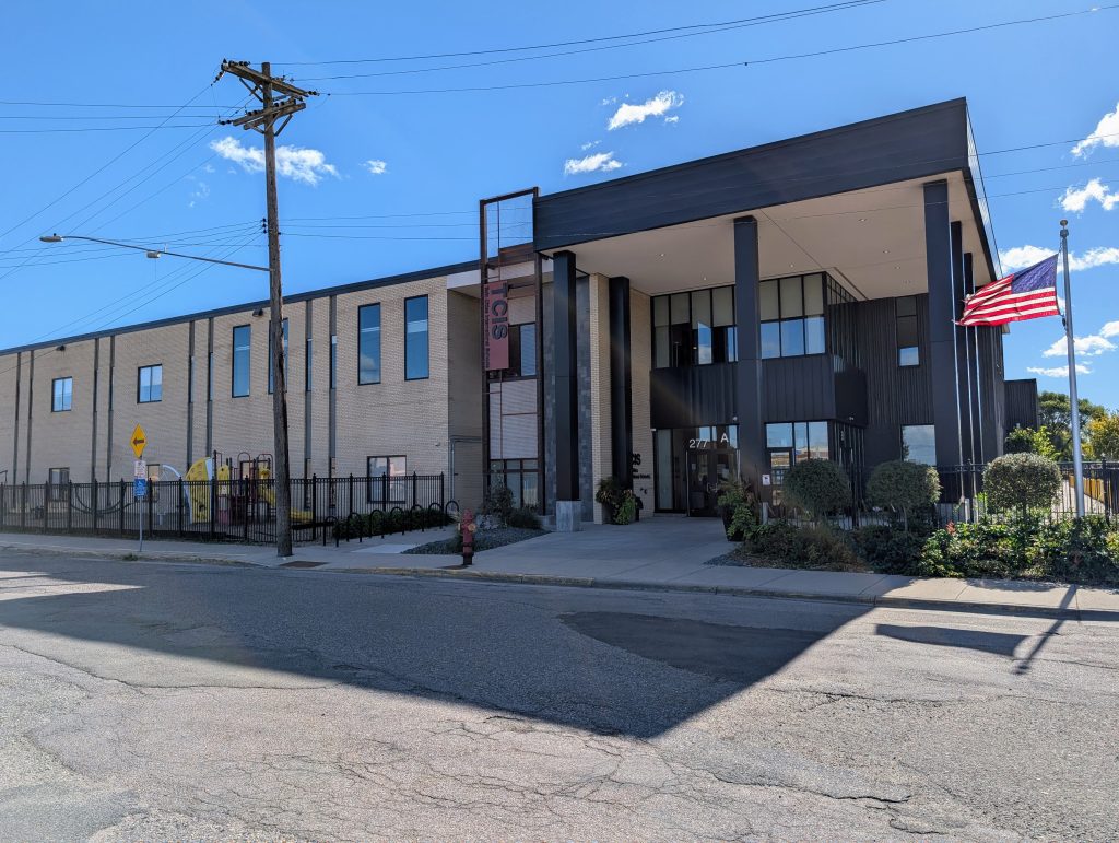 utilitarian two-story building with more recent corner entryway and flag