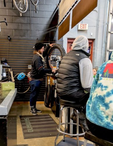 A person holds up a fat tire while attendees look on.