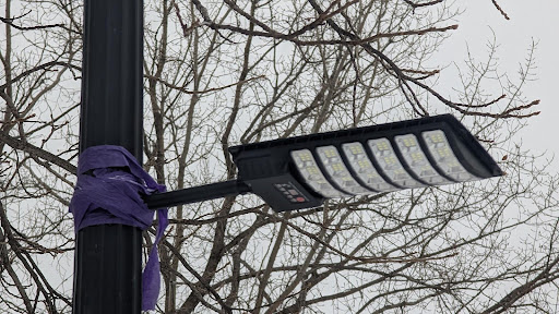 A solar lamp strapped to a light post.