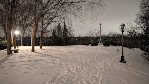 A snow-covered bike path, with a dark street light next to it.