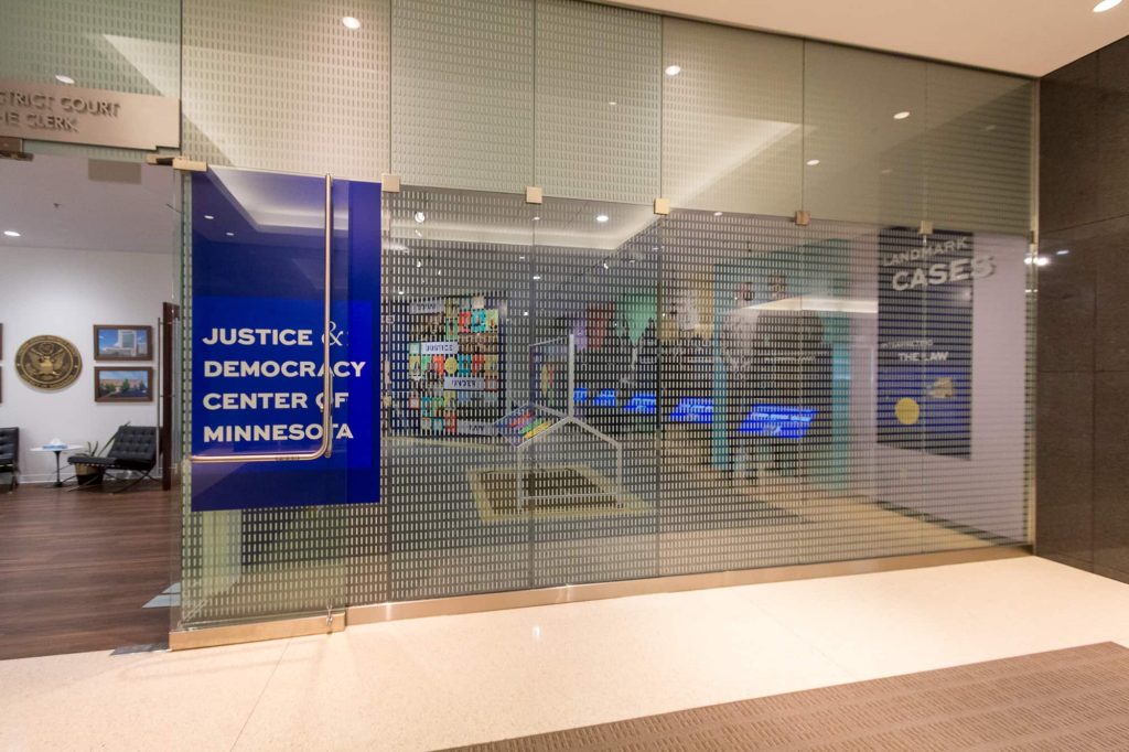 Glass windows and door with Justice & Democracy Center of Minnesota sign.